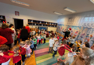 Zdjęcie przedstawia dzieci ustawione w pociągi, które tańcząc przemieszczają się po sali.