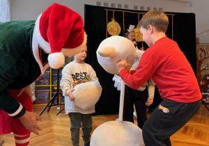 w centrum zdjęcia dzieci wraz z Elfem składają bałwanka z części uszytych z materiału.