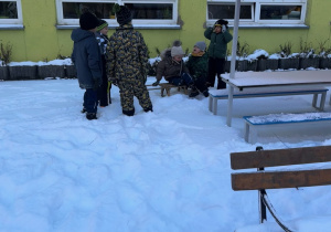 Na zaśnieżonym tarasie przedszkolnym chłopcy z grupy urządzają saneczkowe wyścigi.